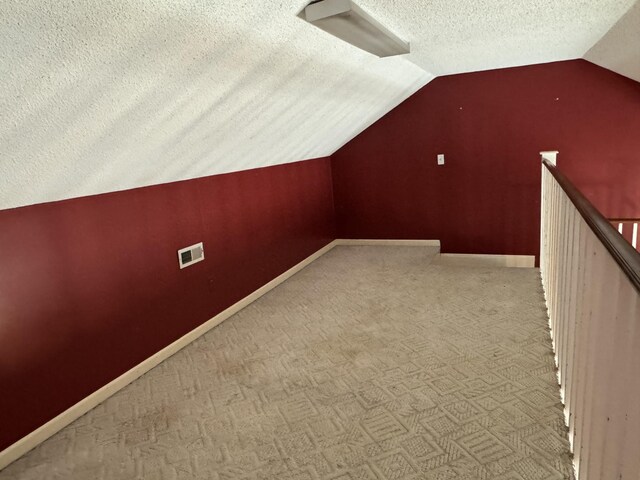 bonus room with vaulted ceiling, light carpet, and a textured ceiling