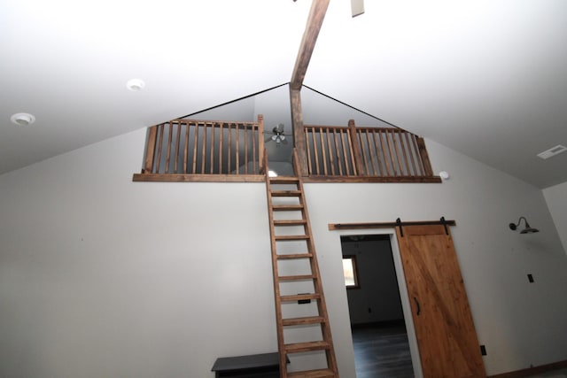 stairs with a barn door, wood-type flooring, and lofted ceiling