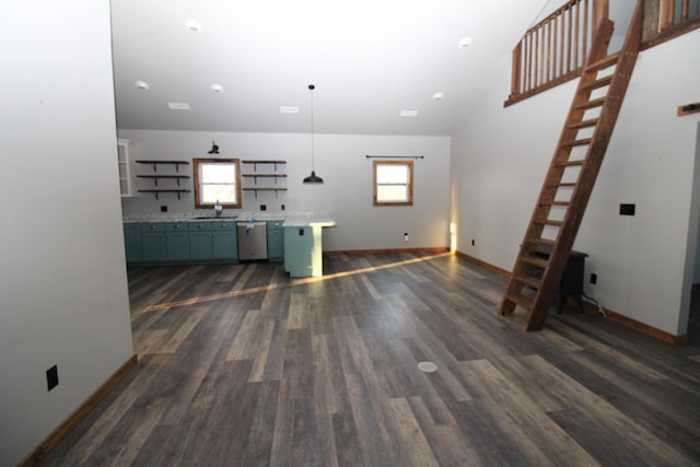 unfurnished living room featuring sink, dark wood-type flooring, a wealth of natural light, and a towering ceiling