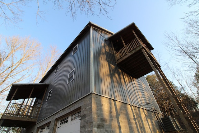 view of side of home featuring a garage, a balcony, and central air condition unit