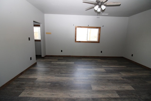 empty room with dark wood-type flooring, ceiling fan, and a wealth of natural light