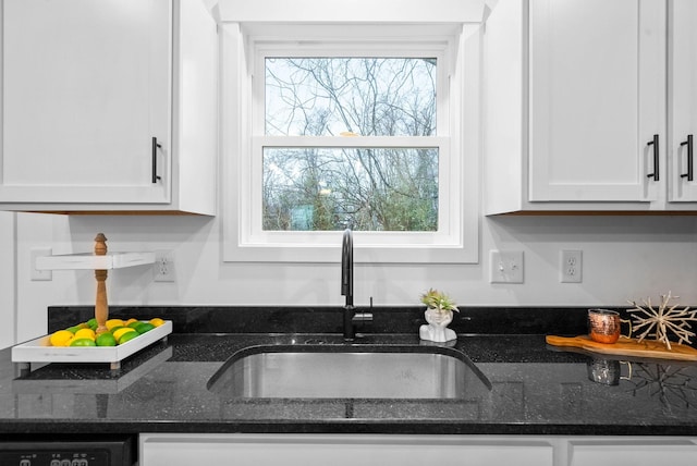 kitchen featuring a healthy amount of sunlight, sink, white cabinets, and dark stone counters