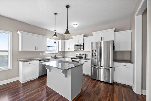 kitchen with white cabinets, appliances with stainless steel finishes, dark wood-style flooring, a center island, and a sink