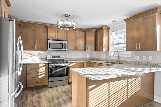 kitchen with appliances with stainless steel finishes, a breakfast bar, pendant lighting, sink, and kitchen peninsula