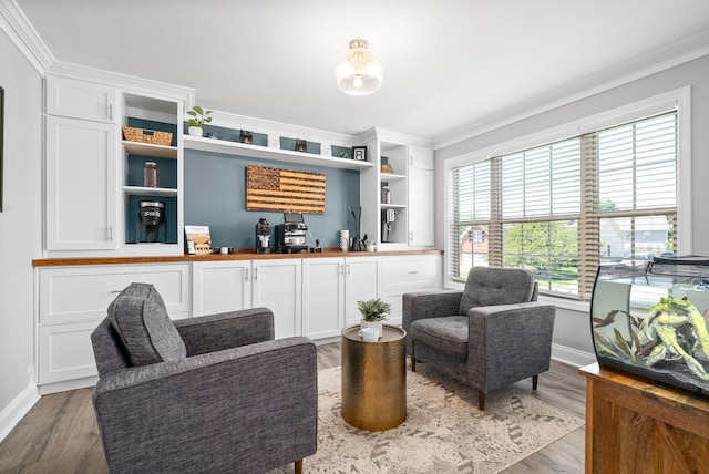 living area featuring baseboards, ornamental molding, and wood finished floors