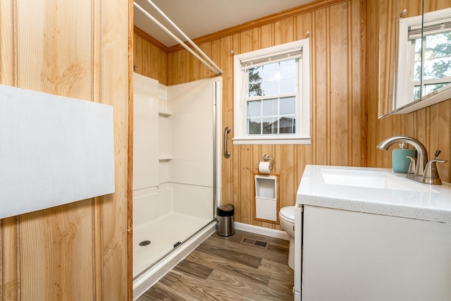 bathroom featuring vanity, walk in shower, toilet, and wood walls