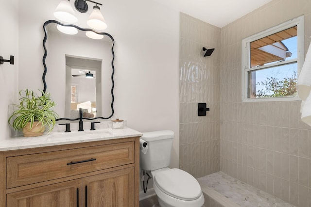 bathroom featuring vanity, tiled shower, and toilet