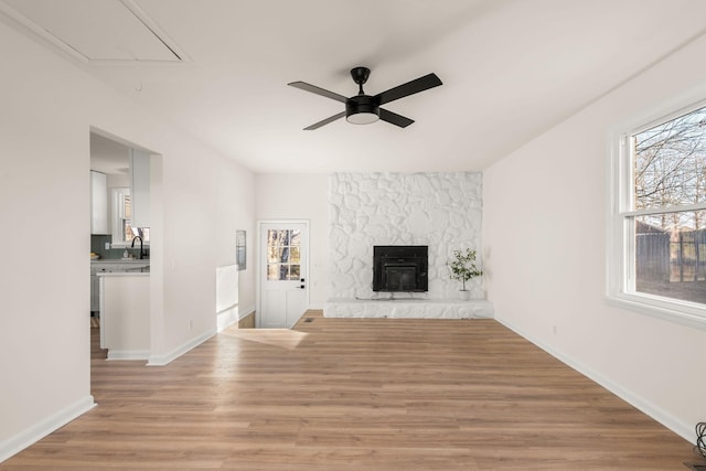 unfurnished living room featuring a fireplace, ceiling fan, and light wood-type flooring