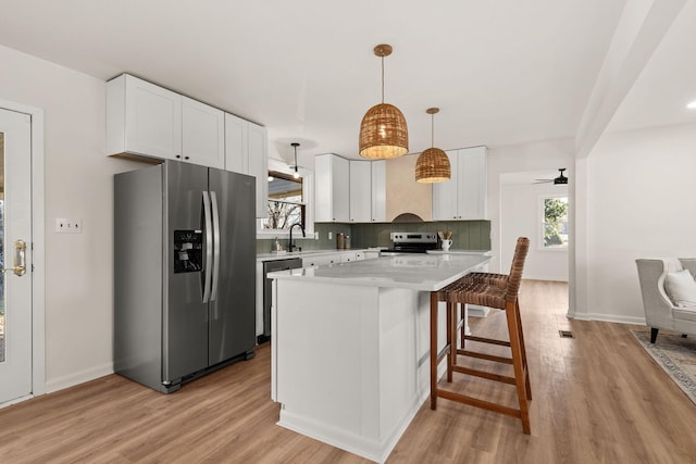 kitchen with hanging light fixtures, appliances with stainless steel finishes, a center island, and white cabinets