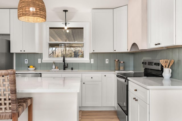 kitchen featuring stainless steel electric range oven, tasteful backsplash, sink, white cabinets, and hanging light fixtures