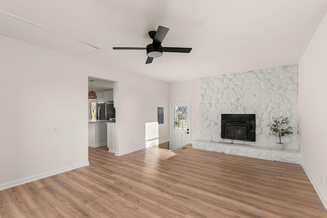 unfurnished living room featuring ceiling fan, a stone fireplace, and hardwood / wood-style floors