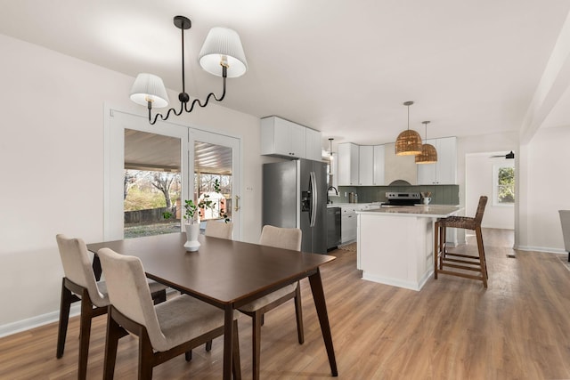 dining space featuring a healthy amount of sunlight, sink, and light hardwood / wood-style floors