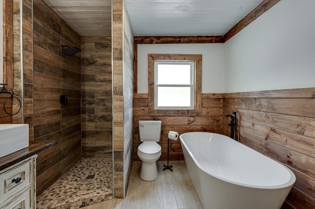 full bath with toilet, a wainscoted wall, vanity, a soaking tub, and a shower stall