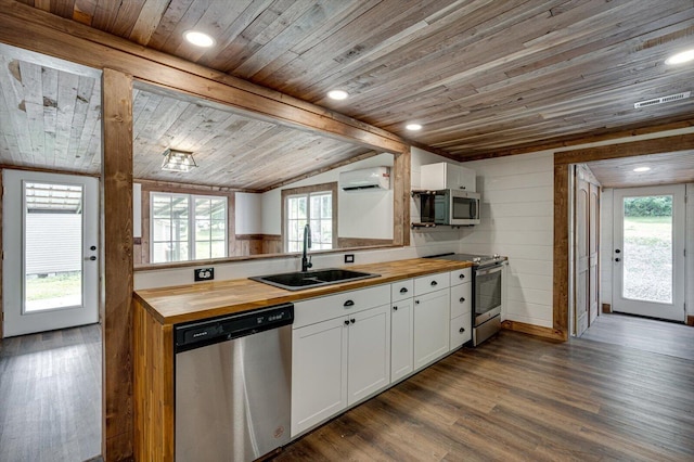 kitchen with appliances with stainless steel finishes, white cabinets, a sink, and wood counters