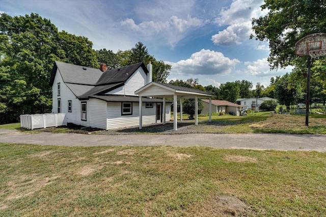 view of front of home with driveway, a chimney, a carport, and a front yard