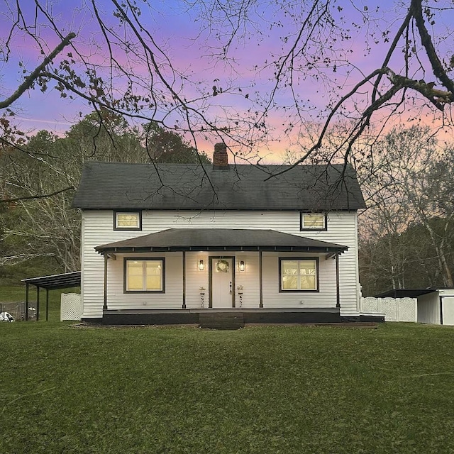 view of front facade with covered porch, a chimney, an outdoor structure, and a yard