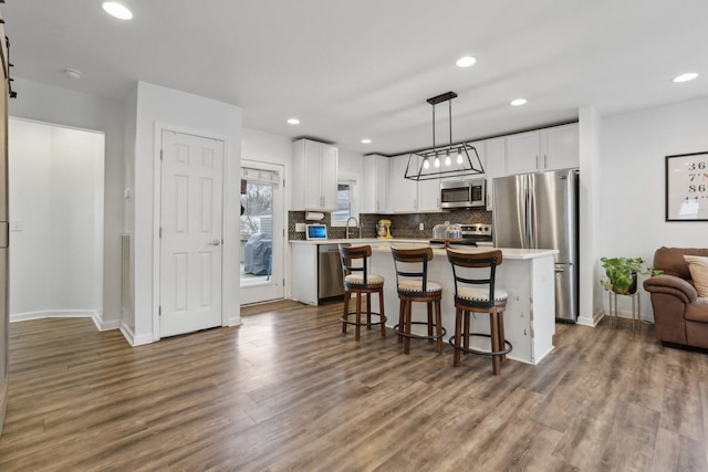 kitchen with hanging light fixtures, stainless steel appliances, a center island, and white cabinets