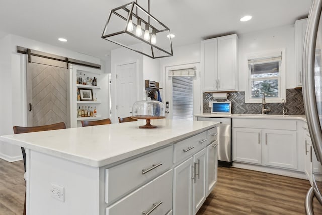 kitchen with a breakfast bar, sink, a kitchen island, pendant lighting, and white cabinets