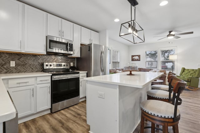 kitchen with decorative light fixtures, white cabinetry, a kitchen breakfast bar, a center island, and stainless steel appliances