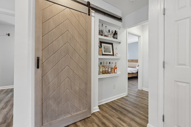 hallway featuring a barn door, hardwood / wood-style floors, and built in features