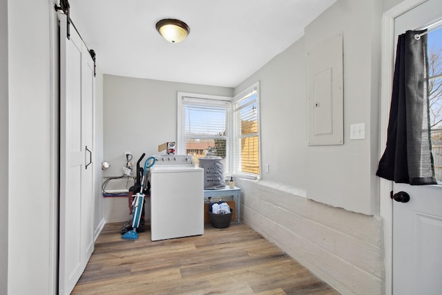 laundry room with light wood-type flooring, washer / dryer, and a barn door