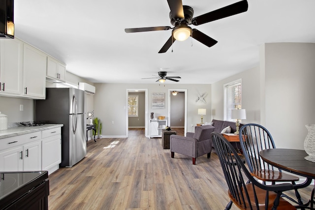 interior space featuring a wall mounted air conditioner, a healthy amount of sunlight, and light wood-type flooring