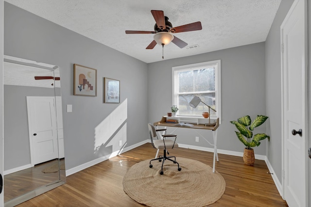 home office with hardwood / wood-style flooring, ceiling fan, and a textured ceiling