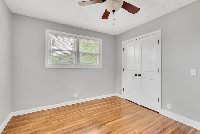 unfurnished bedroom with ceiling fan, a closet, light hardwood / wood-style flooring, and a textured ceiling