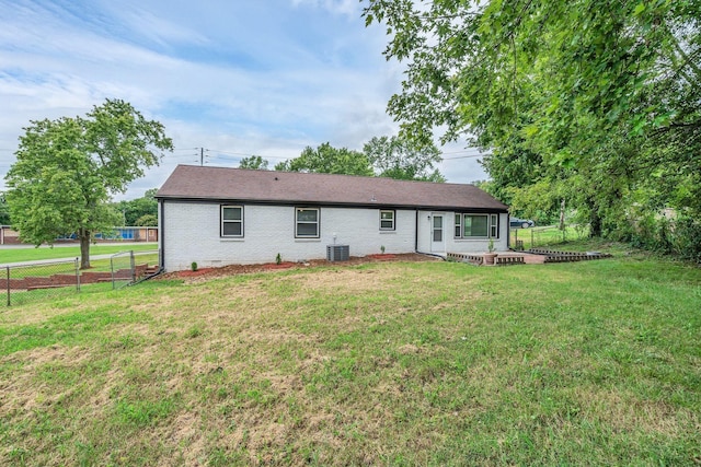 rear view of property with cooling unit and a lawn