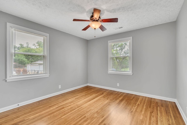 spare room with ceiling fan, light hardwood / wood-style floors, and a textured ceiling