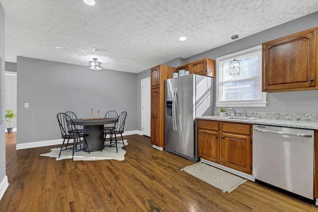 kitchen featuring stainless steel appliances, sink, pendant lighting, and dark hardwood / wood-style flooring