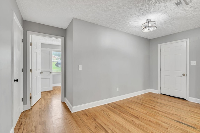 unfurnished room featuring a textured ceiling and light hardwood / wood-style flooring