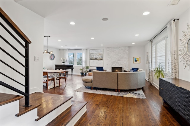 living room with dark hardwood / wood-style flooring, a fireplace, and an inviting chandelier