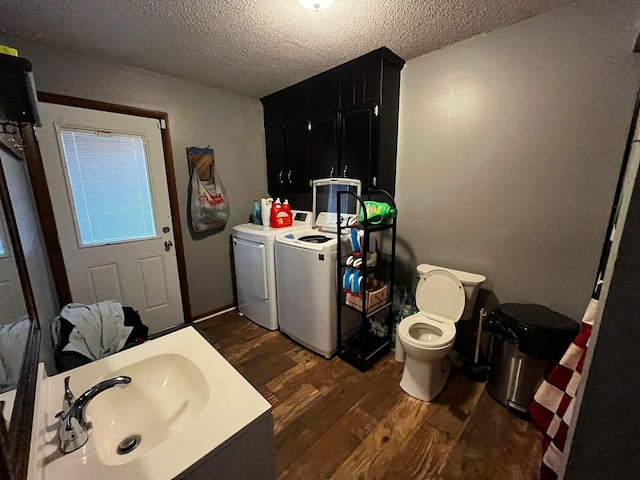 bathroom featuring wood-type flooring, sink, toilet, washing machine and dryer, and a textured ceiling