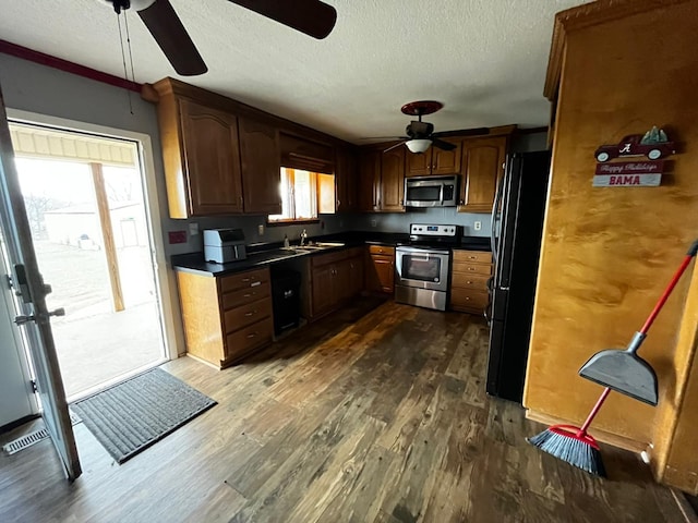 kitchen with sink, a textured ceiling, dark hardwood / wood-style flooring, ceiling fan, and stainless steel appliances