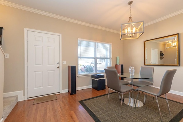 dining area with a chandelier, ornamental molding, wood finished floors, and baseboards