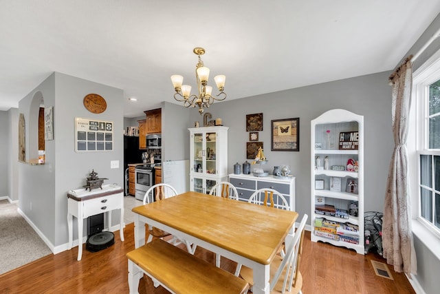 dining area with light hardwood / wood-style floors and a notable chandelier