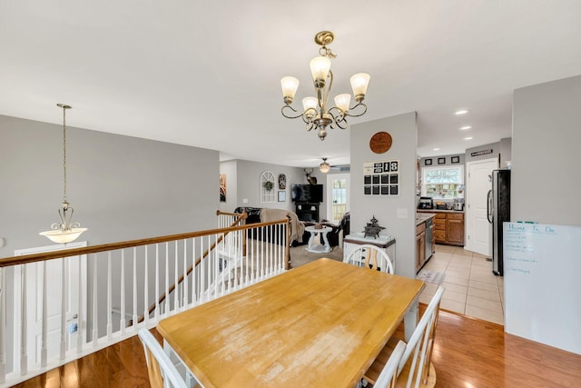 dining space with ceiling fan with notable chandelier and light wood-type flooring