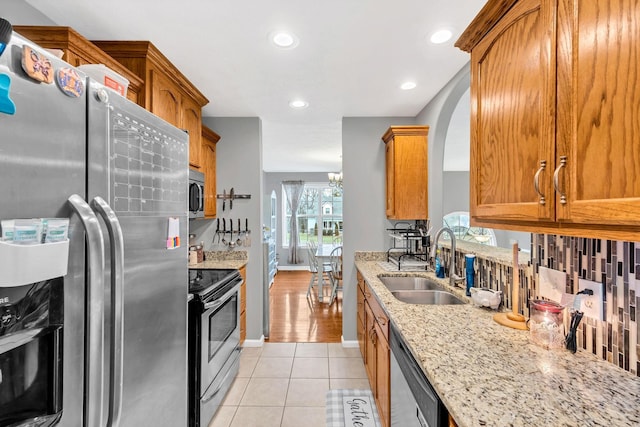 kitchen featuring sink, light stone countertops, stainless steel appliances, and light tile patterned floors