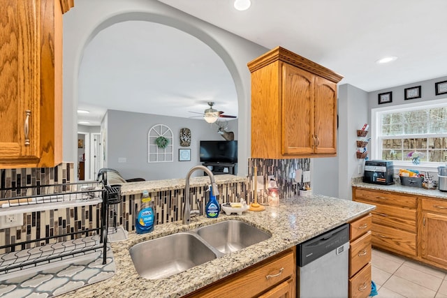 kitchen with light stone countertops, sink, stainless steel dishwasher, and decorative backsplash