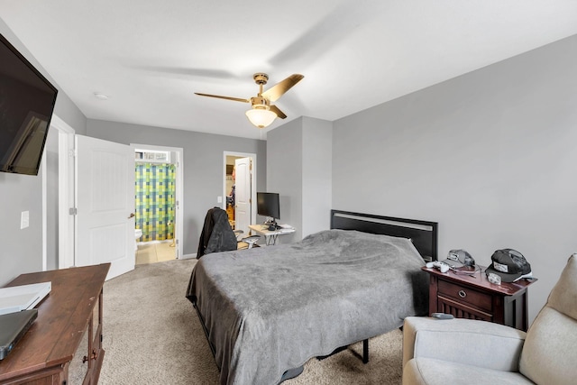 bedroom featuring light colored carpet, ceiling fan, and ensuite bath