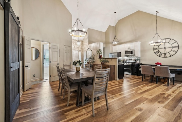 dining area featuring an inviting chandelier, wood-type flooring, and a barn door