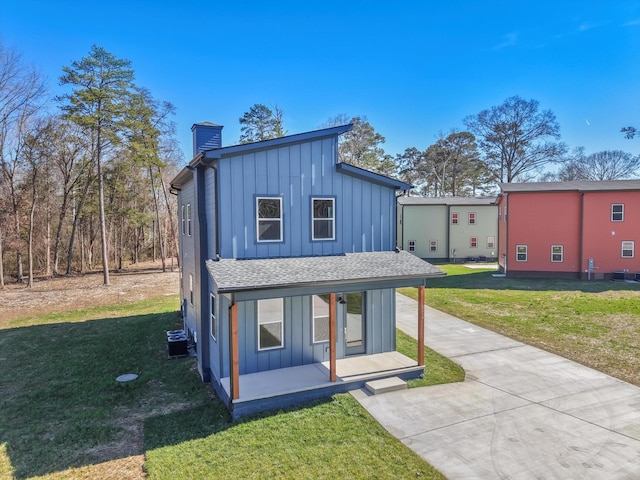 view of front of property with a chimney, board and batten siding, and a front yard