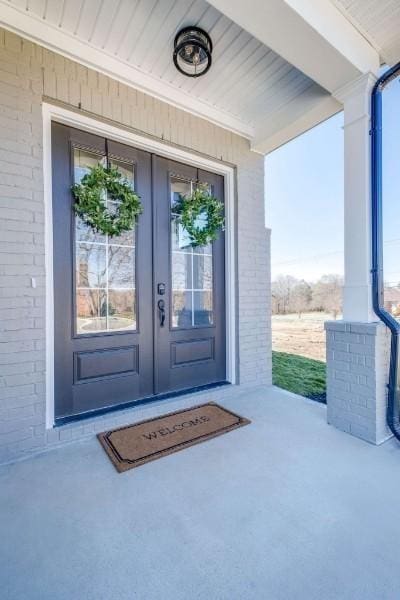 view of exterior entry with brick siding and french doors