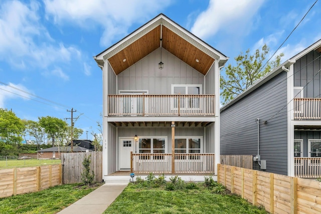 view of front of property featuring a porch, a balcony, and a front lawn