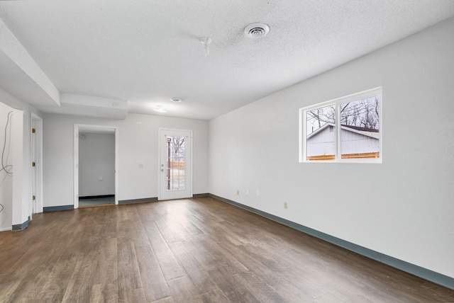 empty room with dark hardwood / wood-style flooring and a textured ceiling