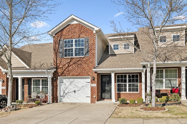 traditional-style home featuring brick siding, driveway, an attached garage, and roof with shingles