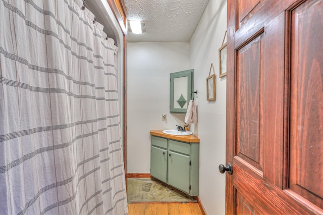 bathroom with wood-type flooring, a textured ceiling, and vanity