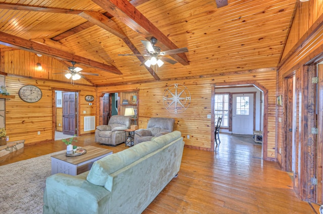 living room featuring wood ceiling, wood walls, beamed ceiling, and light wood-type flooring