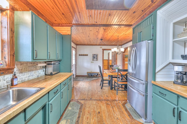 kitchen featuring pendant lighting, stainless steel fridge with ice dispenser, decorative backsplash, and butcher block countertops